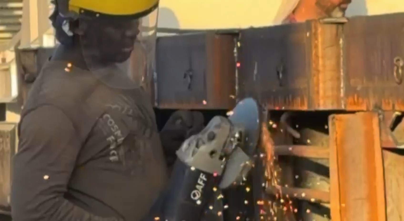 Fabricator angle-grinding a trailer chassis section